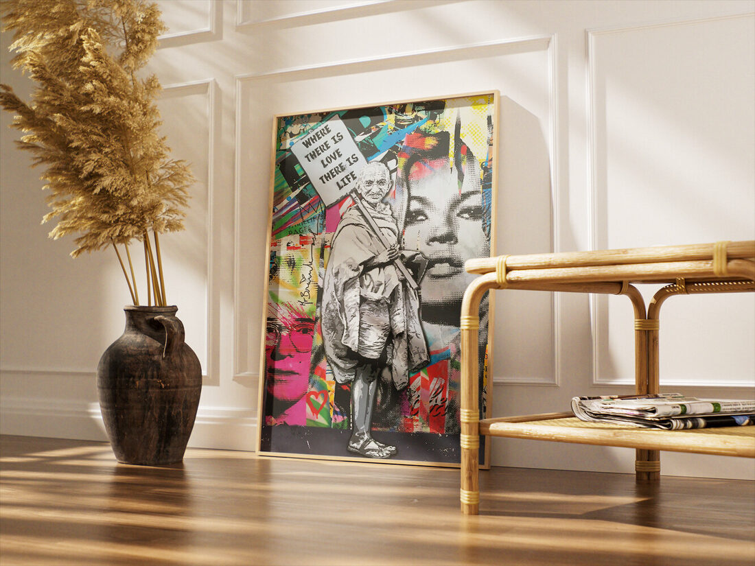 Pop art kolaj: Canlı yüzler ve metin içeren bir arka plan üzerinde, "SEVGİ VARSA HAYAT VARDIR" yazılı bir tabela tutan gri tonlu Gandhi.